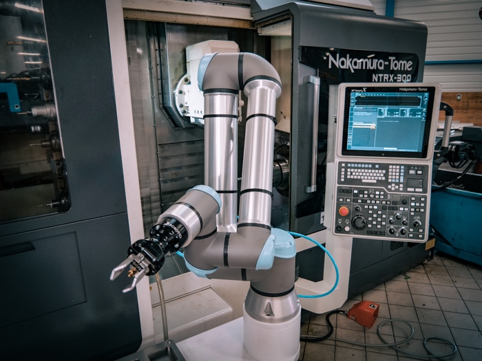 Cobot devant un centre d'usinage CNC